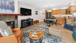 A modern living room with a fireplace, leather sofa, coffee table, and a dining area with chairs and a table.