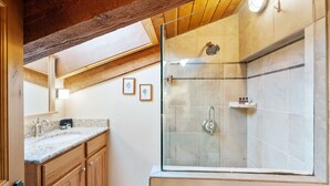 Un baño moderno con ducha de vidrio, armarios de madera y tragaluz.