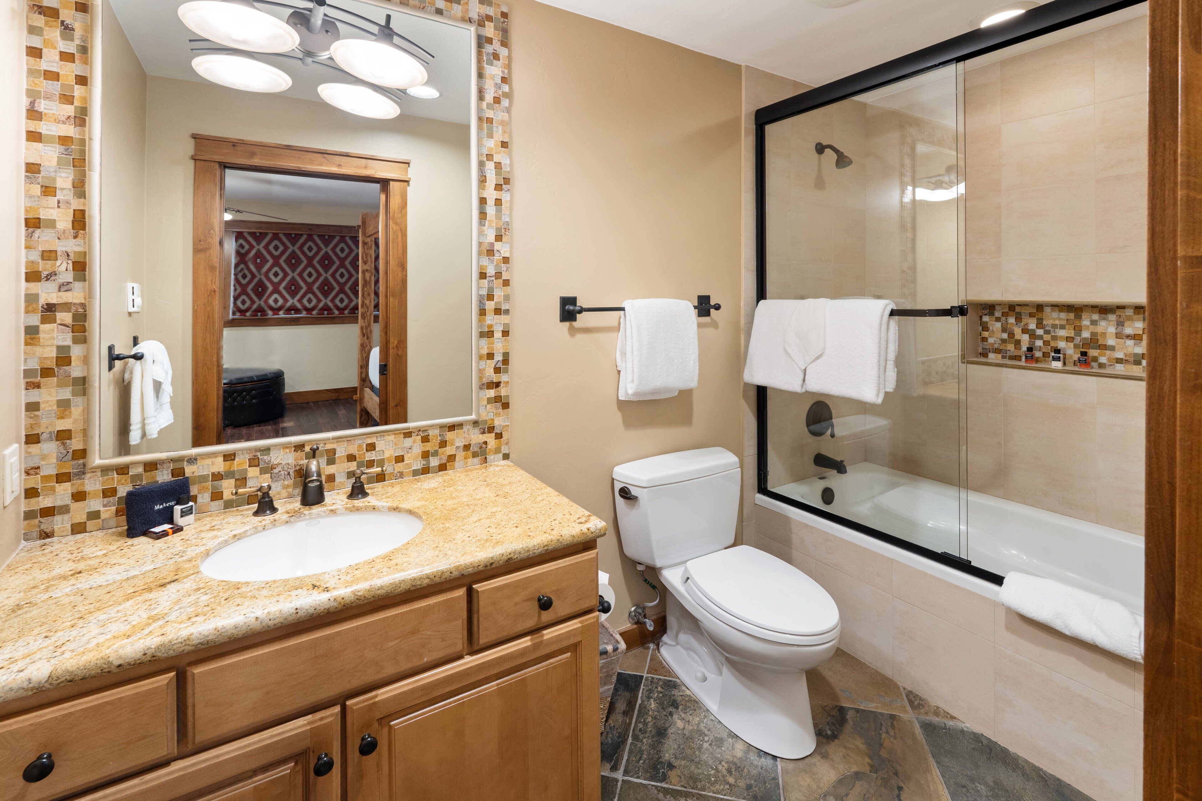 A bathroom with a sink, toilet, and glass-enclosed shower.