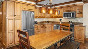 Una cocina amplia con armarios de madera, un refrigerador de acero inoxidable, un microondas y una mesa de comedor de madera con sillas.