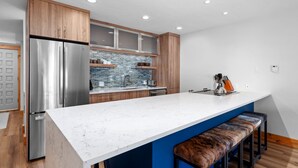 Una cocina moderna con una isla grande, armarios de madera y un refrigerador de acero inoxidable.