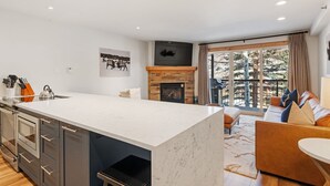 Una cocina moderna con una isla grande, una chimenea y un área de comedor con sofá y mesa.