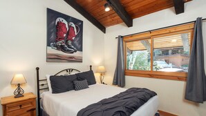 Une chambre à coucher avec un lit, deux tables de chevet, une lampe, un tableau et une fenêtre avec des rideaux.
