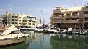 A marina with multiple boats docked, surrounded by multi-story buildings with balconies and a distinctive dome structure. - Spacious Apartment With all Facilities Just a few Metres From the Beach (Benalmádena)