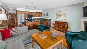 A modern living room with a grey sofa, a wooden coffee table, and a teal armchair.