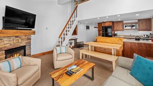 Un salon moderne avec une cheminée, un téléviseur à écran plat et un banc en bois.