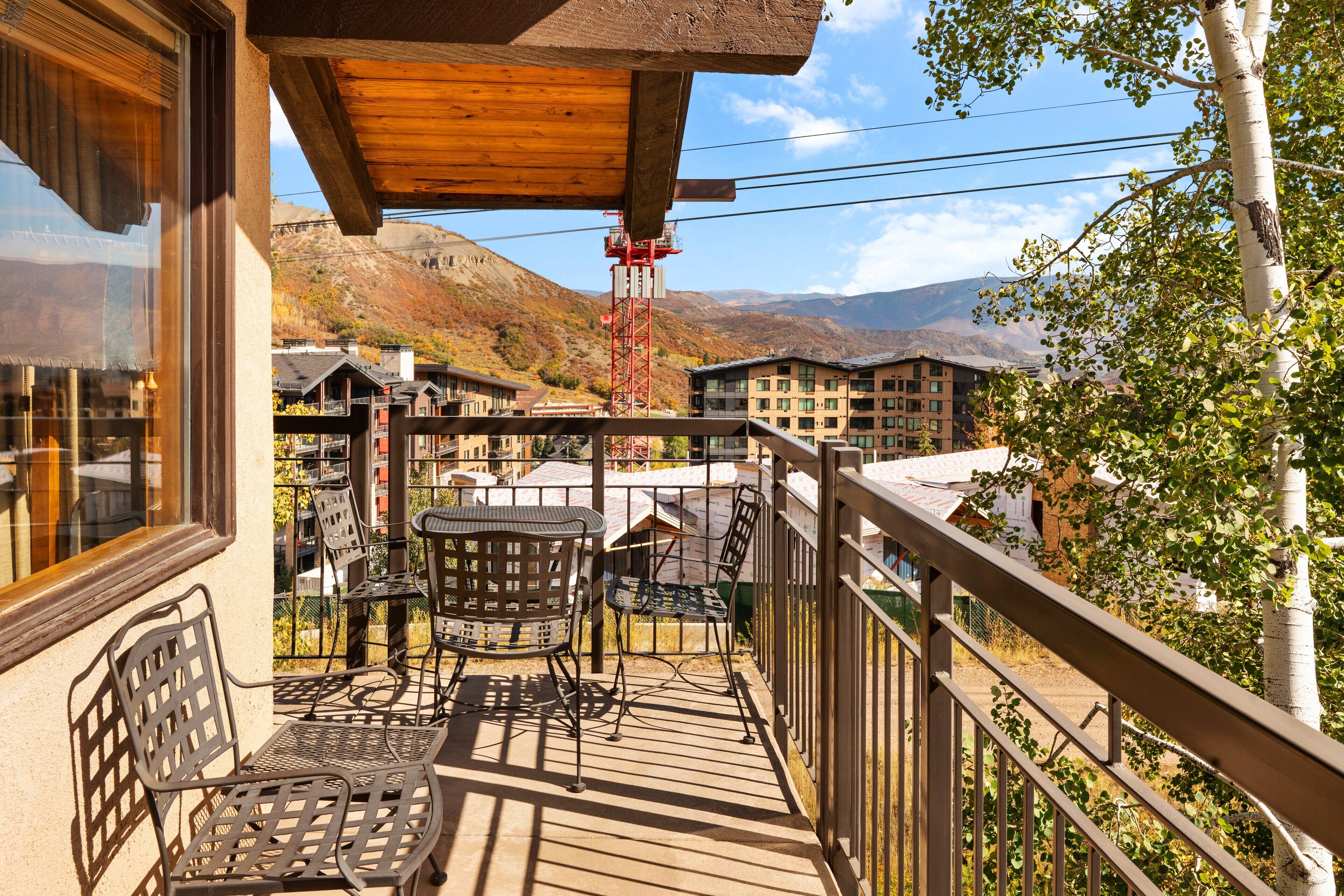 A wooden deck with outdoor seating, overlooking a mountainous landscape.