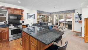 A modern kitchen with granite countertops, wooden cabinets, and stainless steel appliances. - Crestwood 2108 Deluxe 2 Bedroom (Snowmass Village)