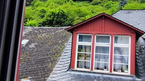 Ein Gebäude mit rotem Dach und einem Fenster, aufgenommen durch ein Fenster mit schwarzem Rahmen.