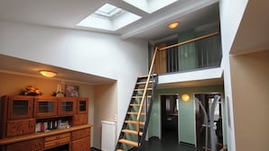 Ein Loft-Zimmer mit Oberlicht, Holzmöbeln, einer Wendeltreppe und Blick auf eine erhöhte Ebene.
