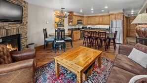 A spacious living room with a fireplace, leather sofa, wooden coffee table, and a large rug. - Crestwood 2109 Premier 2 Bedroom (Snowmass Village)