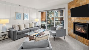 A modern living room with a fireplace, a sofa set, a coffee table, and a TV mounted on the wall.
