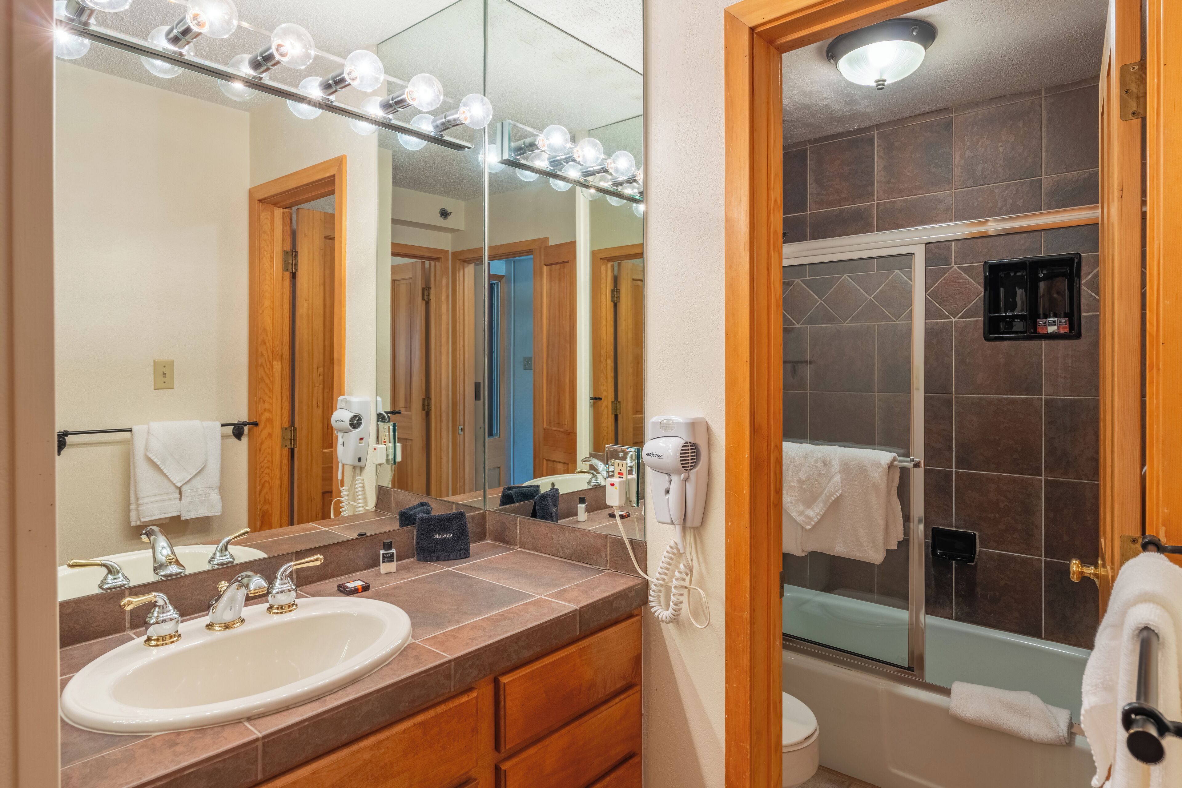 A bathroom with a sink, vanity, mirror, and a shower area.