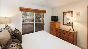 A bedroom with a bed, a dresser, a television, and a window with blinds. - Crestwood 2117 Standard 2 Bedroom (Snowmass Village)