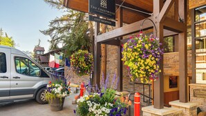 Zona de recepción para huéspedes en The Crestwood, con una estructura de madera, cestas de flores colgantes y una furgoneta estacionada.