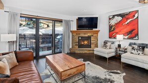 Una sala de estar moderna con chimenea, sofá de cuero y televisor grande.