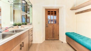 A compact kitchen with a wooden door, a bench, and a sink with modern fixtures.