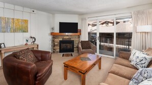 Una sala de estar con chimenea, sofás de cuero, una mesa de centro y un televisor.