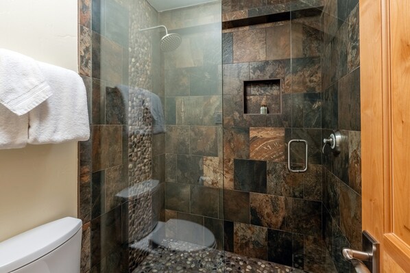Un baño con ducha, inodoro y perchero para toallas.