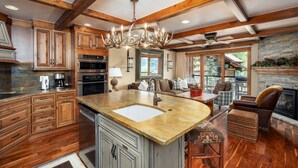 A spacious kitchen with wooden cabinets, a large island with a sink, and a fireplace.