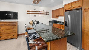 A kitchen with a central island, wooden cabinets, a stainless steel refrigerator, and a mounted knife rack.