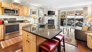 A modern kitchen with wooden cabinets, stainless steel appliances, and a central island with stools.