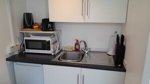 A compact kitchen with a microwave, sink, and cabinets. - Rural Cabin with Outstanding Views (Co)