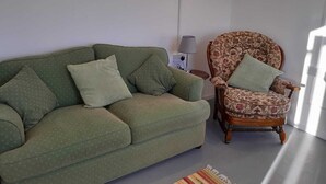 A living room with a green sofa, a floral armchair, and a patterned rug. - Rural Cabin with Outstanding Views (Co)