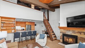 Una sala moderna con chimenea, una zona de cocina y una escalera.