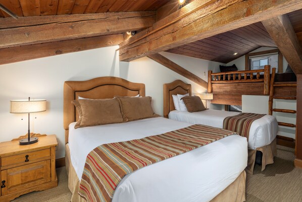 Une chambre avec deux lits, des têtes de lit en bois, une table de chevet et une fenêtre.