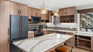 Una cocina moderna con armarios de madera, una isla grande e iluminación colgante.