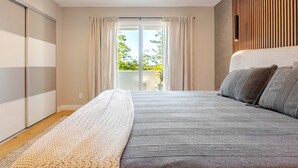 Un dormitorio con una cama grande, vistas al exterior y una puerta corredera al balcón.