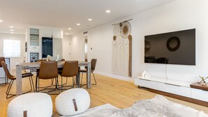 Una cocina moderna con armarios blancos, una mesa de comedor de madera y sillas marrones.