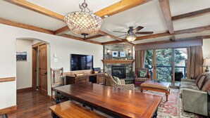A spacious living area with a large wooden dining table, a fireplace, and a cozy seating arrangement.