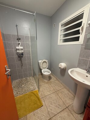 A bathroom with a shower, toilet, sink, and a window with blinds. - GITE HOTEL LA CAZ DES ORANGERS (Saint-Paul)