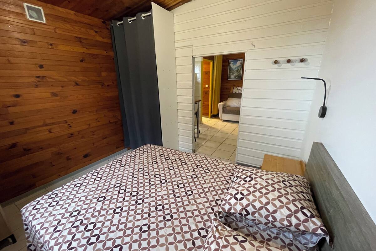 Un dormitorio con una colcha estampada, techo de madera y vistas a otra habitación.