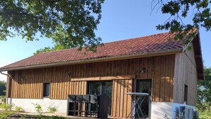 Ein hölzernes Scheunengebäude mit roten Ziegeln auf dem Dach, einem überdachten Sitzbereich und einer großen Klimaanlage.