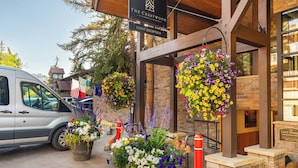 A guest reception area at The Crestwood, featuring a wooden structure, hanging flower baskets, and a parked van. - Crestwood 3108 Premier 2 Bedroom (Snowmass Village)
