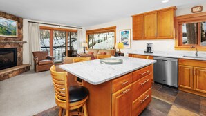 A spacious kitchen with wooden cabinets, a marble island, and a dishwasher.