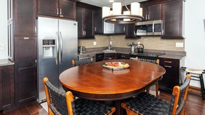 Una cocina moderna con armarios de madera oscura, electrodomésticos de acero inoxidable y una mesa de madera redonda con sillas.