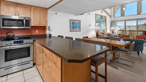 Una cocina moderna con electrodomésticos de acero inoxidable, una isla grande y una zona de comedor con vistas.