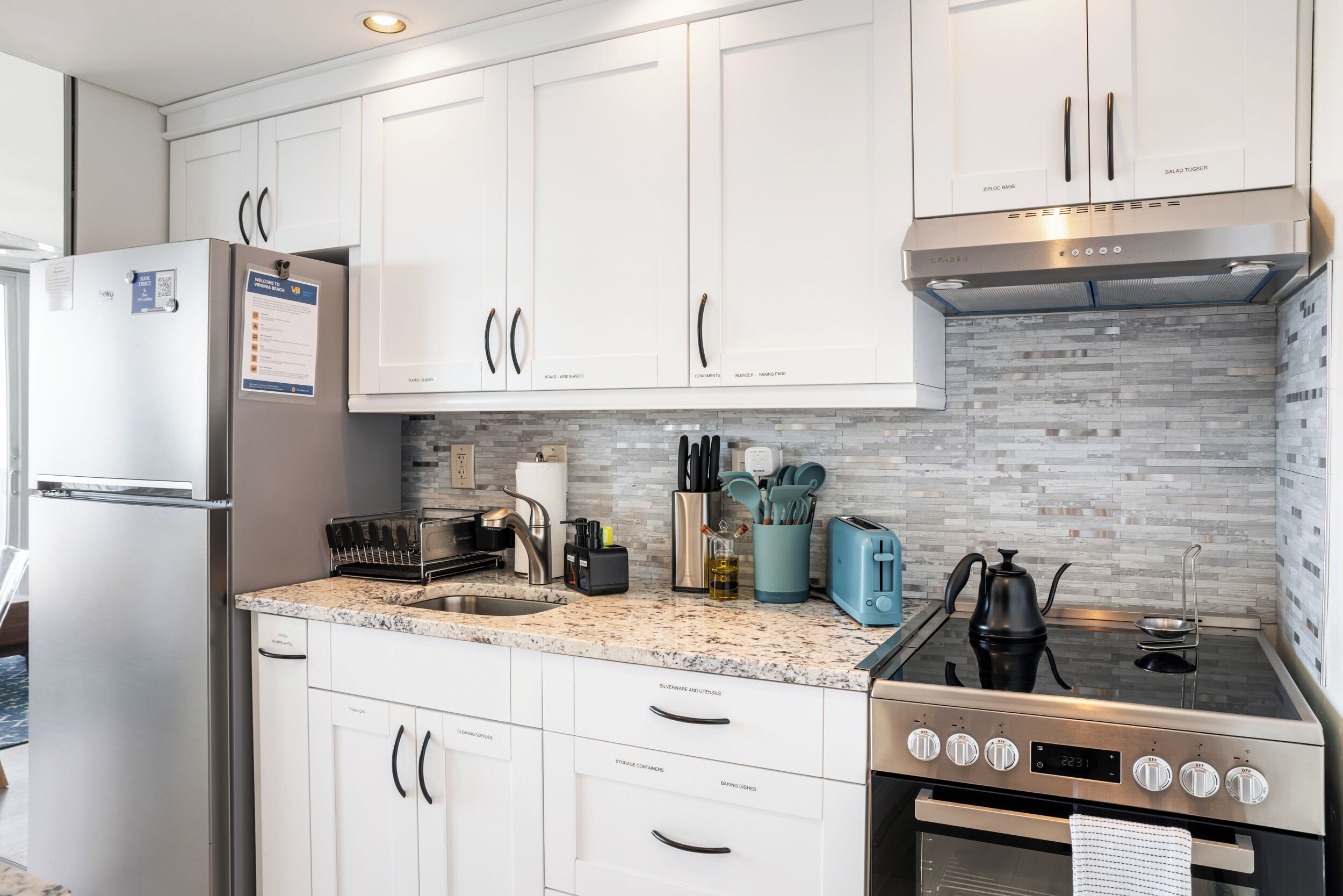 A modern kitchen with white cabinetry, a stainless steel refrigerator, a built-in stove, and a dishwasher.