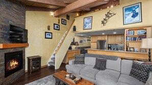 Una sala de estar acogedora con chimenea, un sofá gris y una mesa de centro de madera.