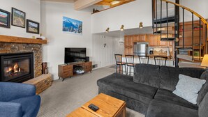 Ein modernes Wohnzimmer mit Kamin, einer Couch, einem Couchtisch und einem Fernseher.
