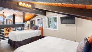 Ein Zimmer mit zwei Betten, Holzbalken, einem Fernseher und einem Fenster.