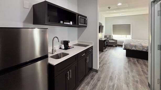 A modern kitchen with a built-in refrigerator, a coffee maker, and a microwave. - Studio 6 Dallas, TX – Fair Park (Dallas)