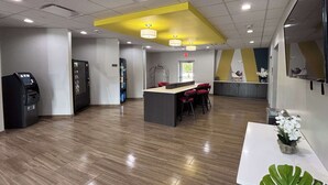 A modern interior with a reception desk, vending machines, and a bar area with stools. - Studio 6 Dallas, TX – Fair Park (Dallas)