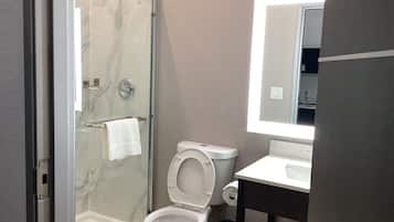 Een badkamer met een douche met glazen wand, een toilet en een wastafel met spiegel erboven.