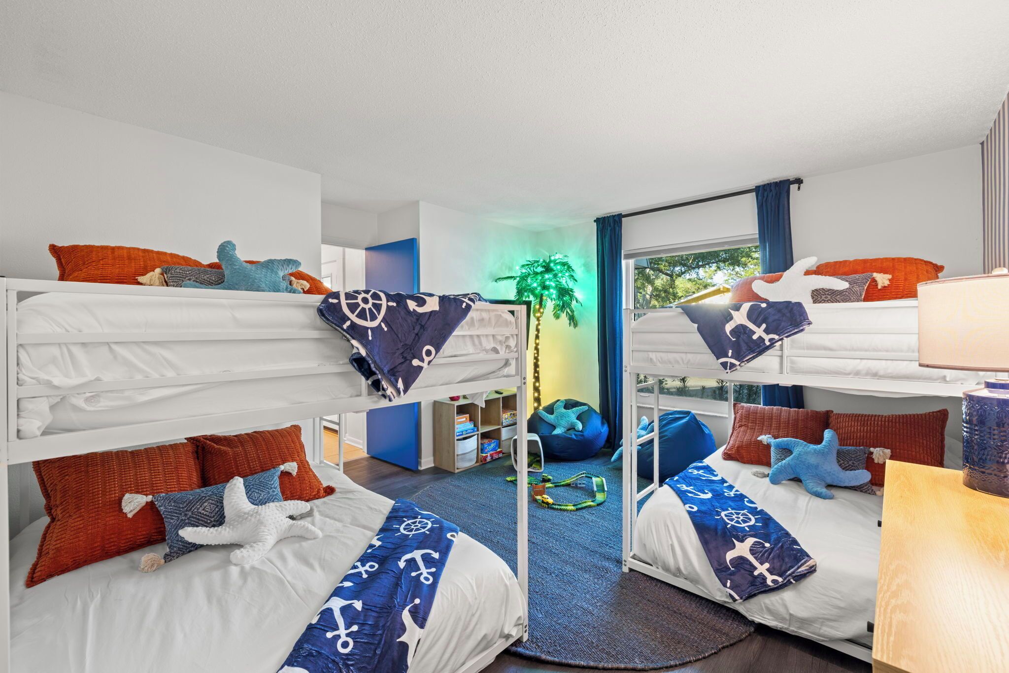 Une chambre avec des lits superposés, une literie sur le thème de la marine, un petit bureau et une vue sur l’extérieur.