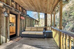 Eine Holzterrasse mit einer Couch und einem Coca-Cola-Schild, das zu einem Küchenbereich führt.